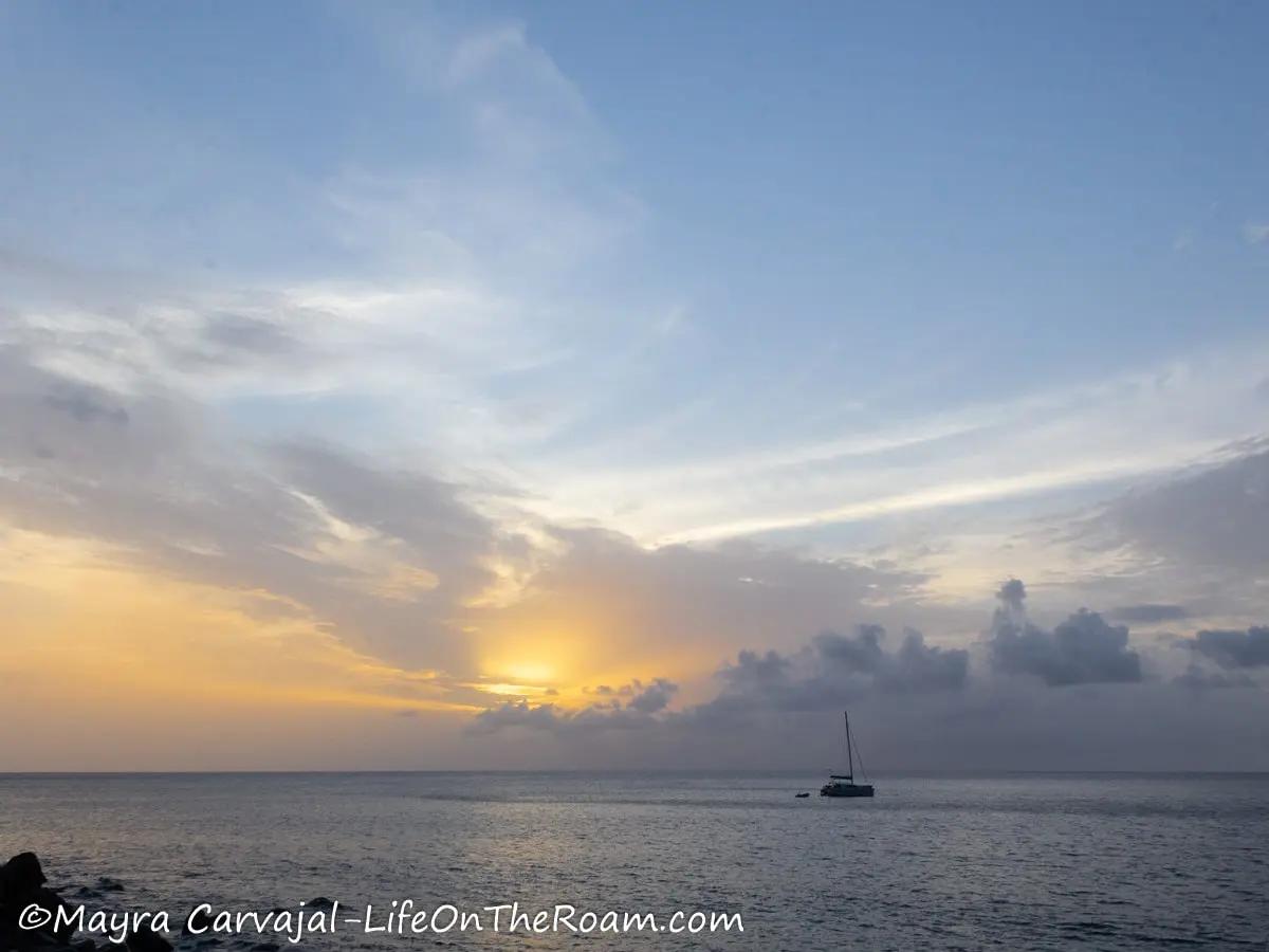 A sunset over the water on Saba island with a boat in the horizon
