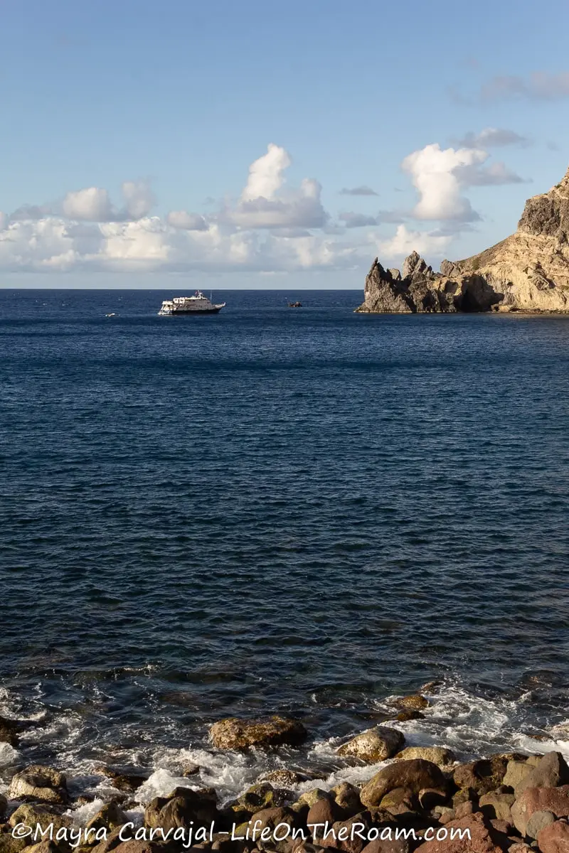 A boat in the sea approaching a cliff on Saba