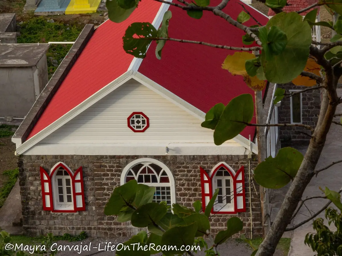 A church in traditional Caribbean style with gothic-style windows with red trim and a pitched red roof