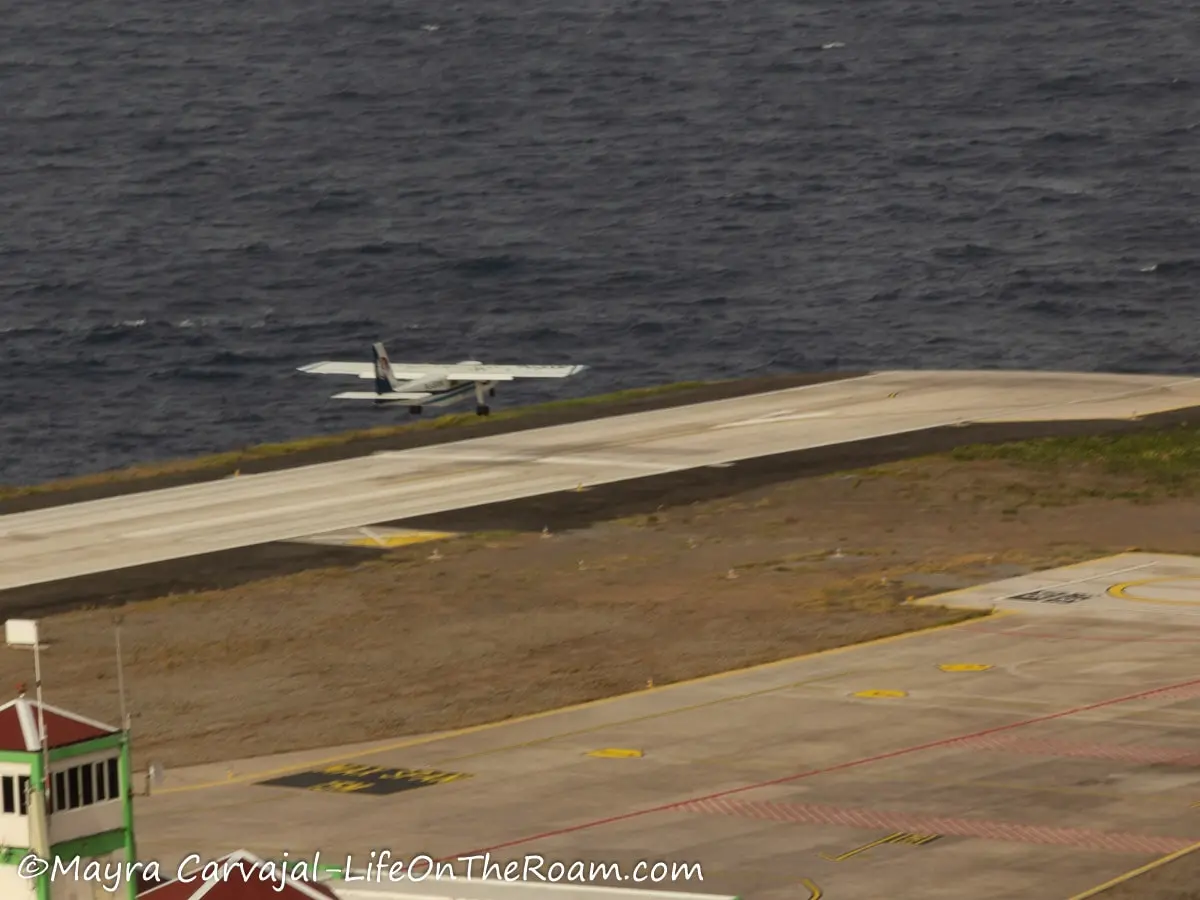 A small plane taking off at the end of a runway next to the sea