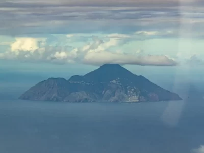 An aerial view of Saba island with its conical shape and a cloud on top