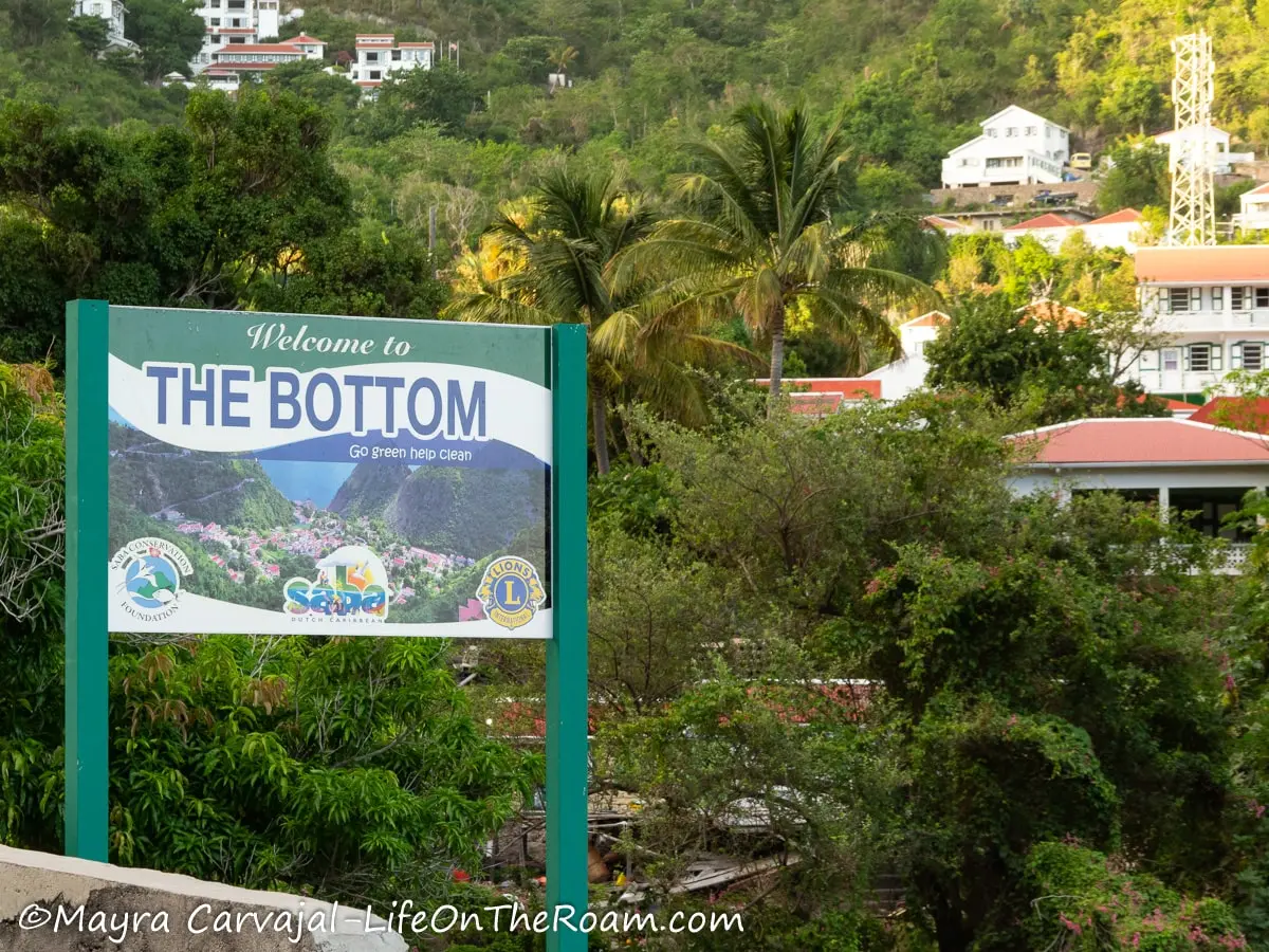 A sign saying "The Bottom" with the background of a village in the mountain