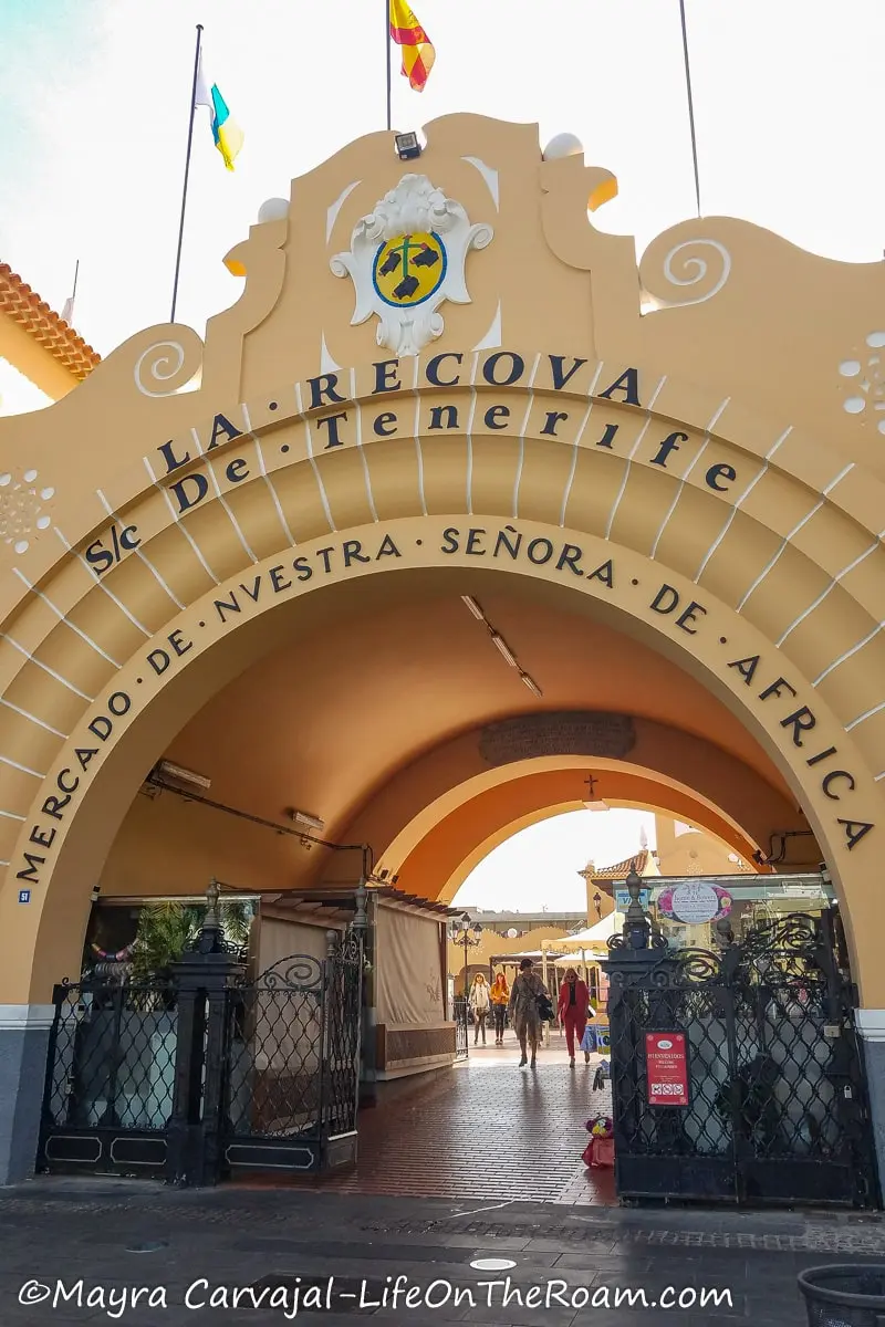 An entrance arch in concrete with black letters saying "La Recova Mercado de Nuestra señora de Africa"
