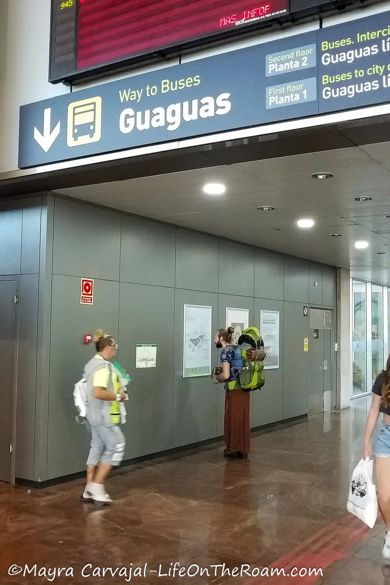 The hall of a bus station with a timetable and a sign reading Guaguas