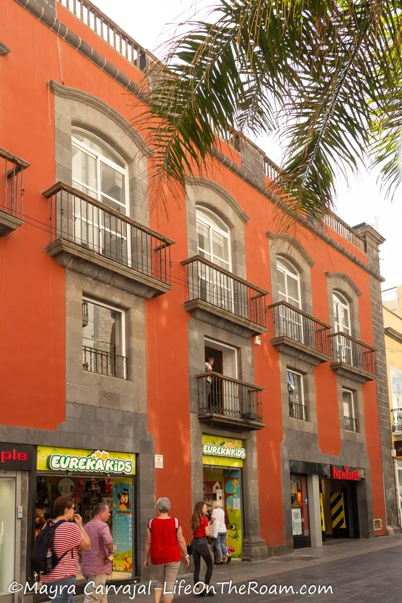 A red brick colour three-story building with balconies