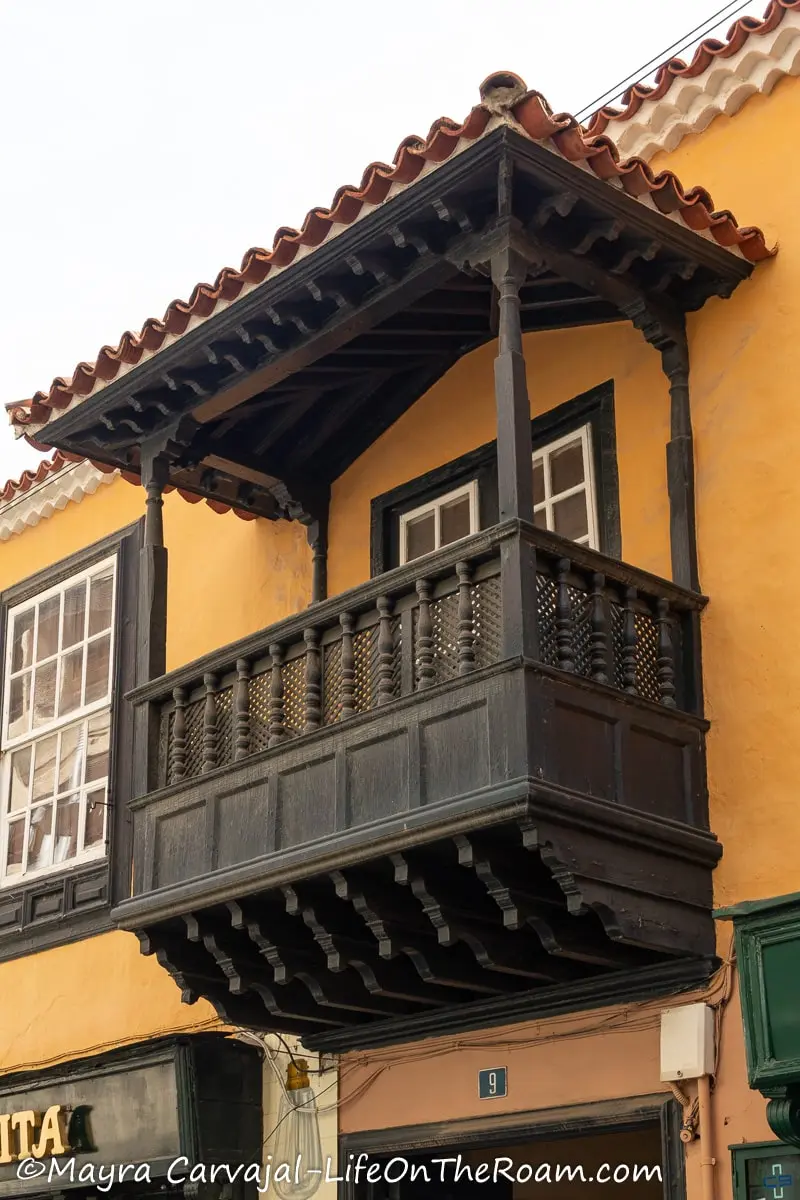 A wooden balcony with Mudejar style elements on a yellow building
