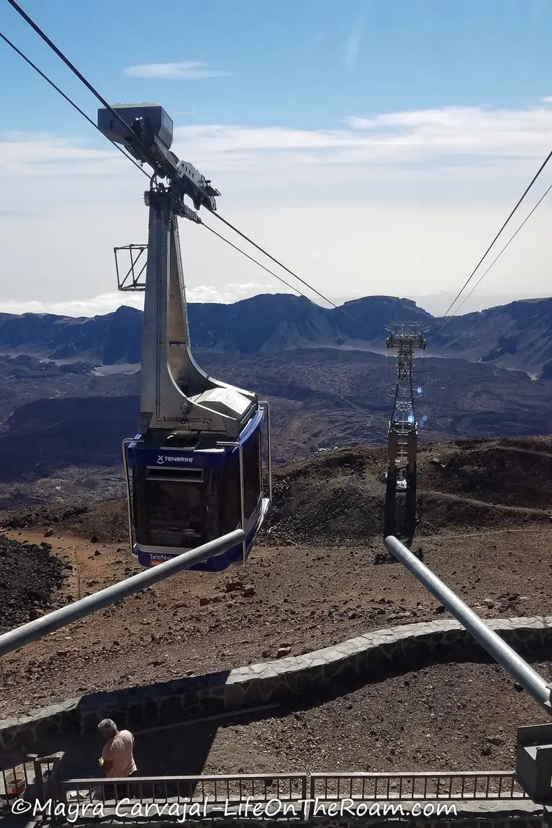 A cable car cabin at the top of a station with a mountainous landscape in the distance