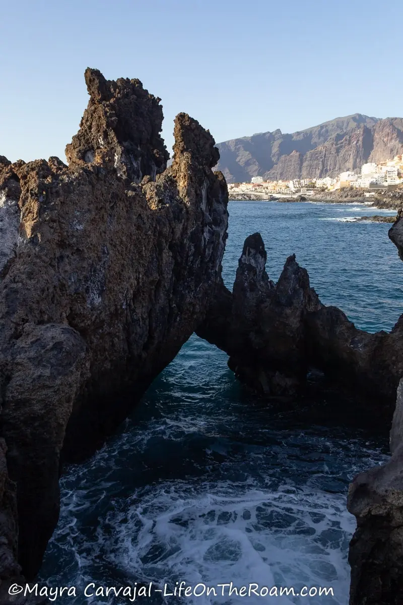 A rock formation in the shore forming an open cave cove