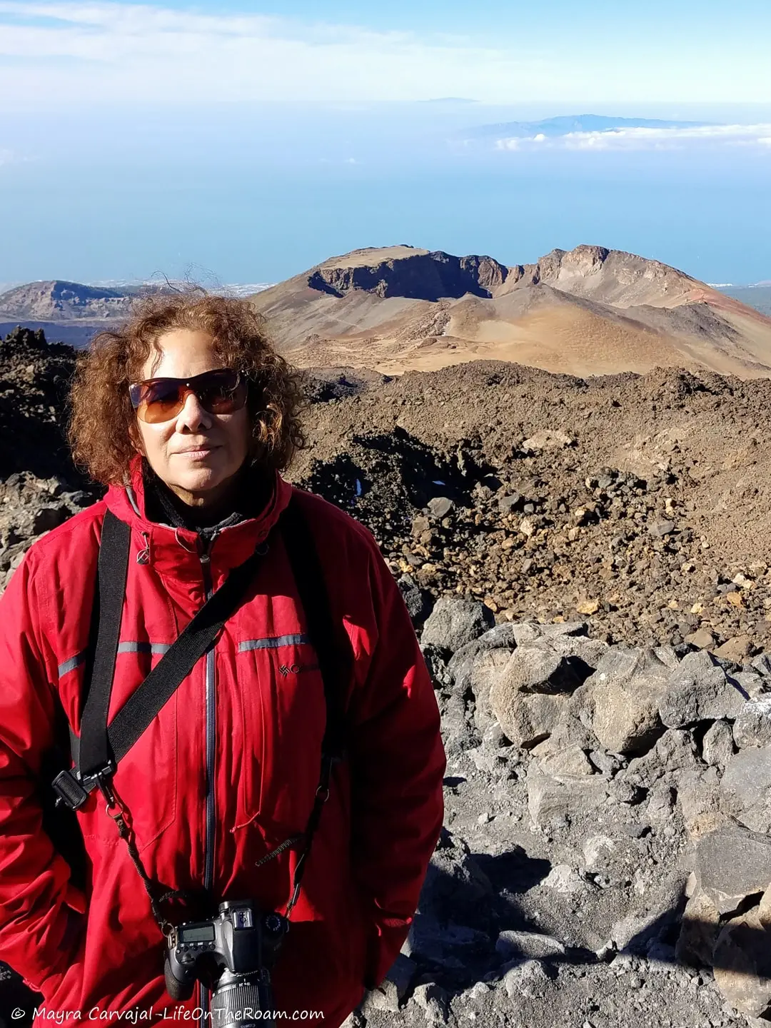 Mayra standing at a viewpoint overlooking the crater of a volcano