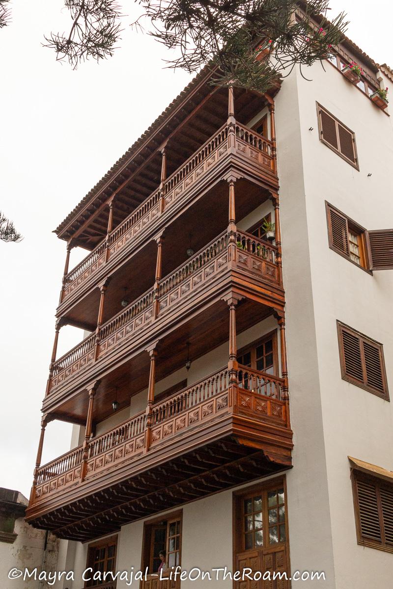 A 4-story building painted in white with  carved wood balconies