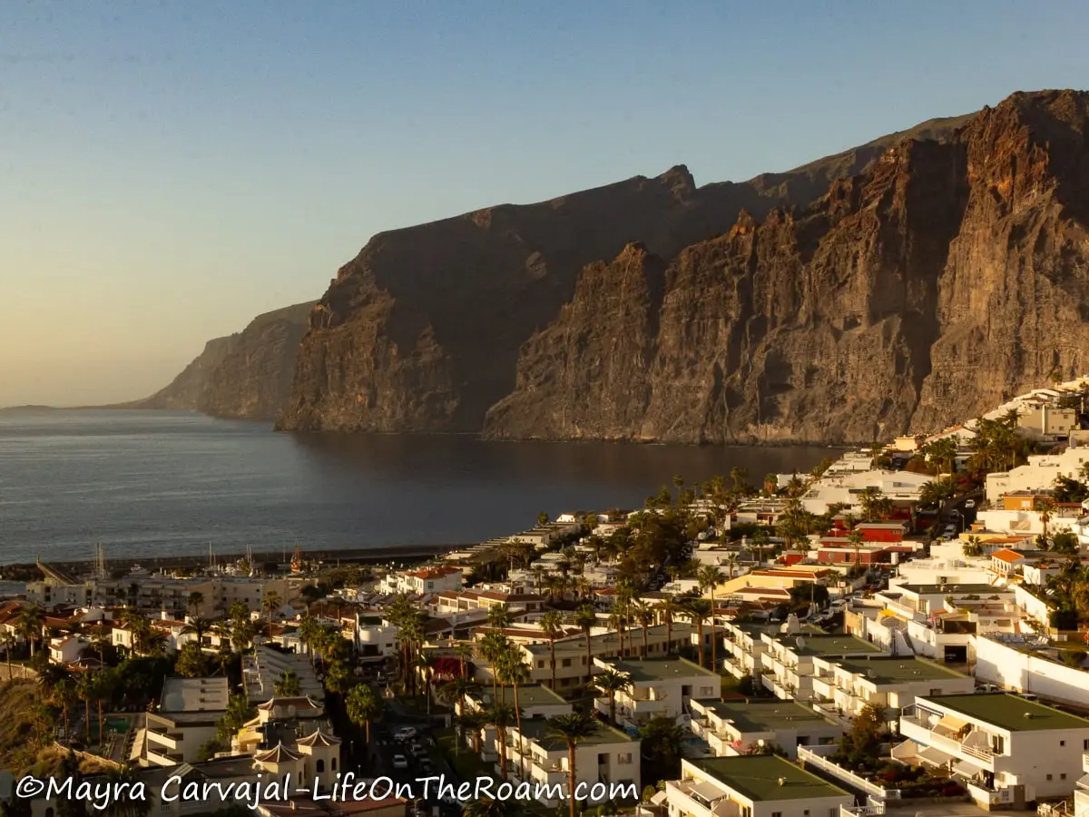 View of monumental sea cliffs in the background with low-rise buildings in the foreground