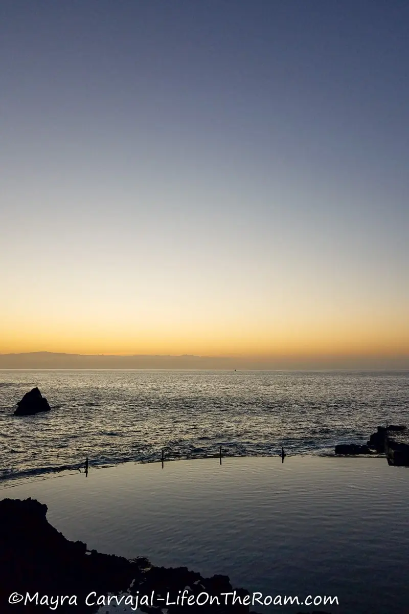 A sunset over the sea from a calm natural pool