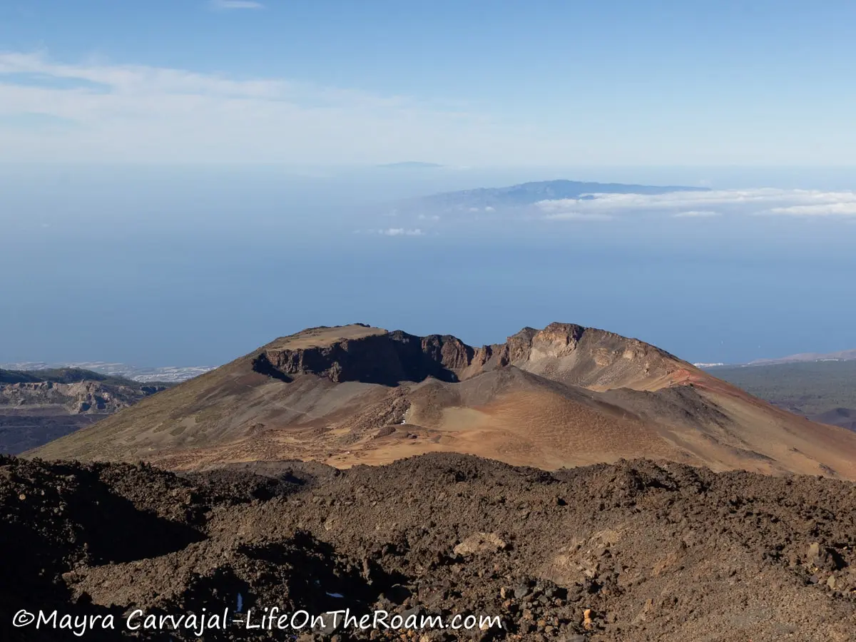 The crater of a volcano with a view of the sea and other islands in the  background 