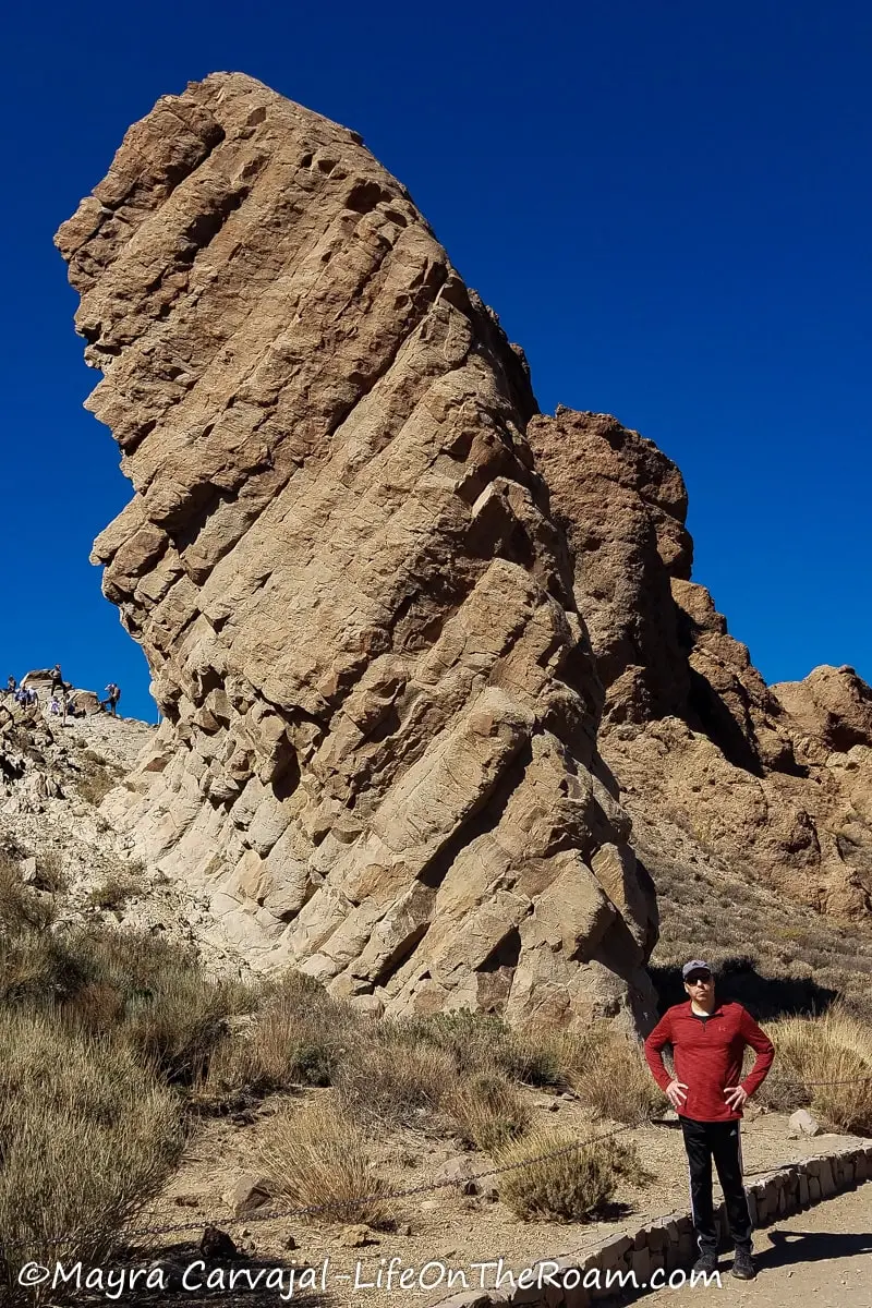 A hiker standing next to a tall and thin rock formation