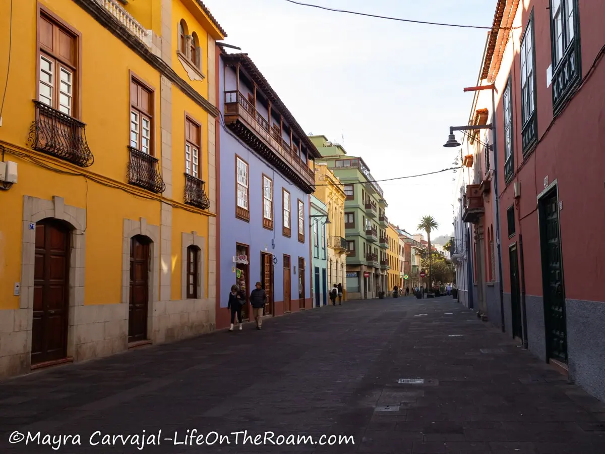 A cobblestone street with low height traditional buildings painted in bright colours