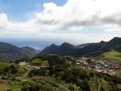 A view of a town over the mountains with the sea in the distance