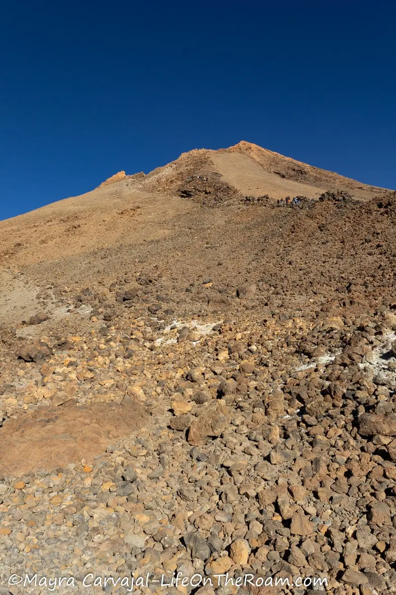 Hikers on a steep trail on the way to reach the summit of a volcano