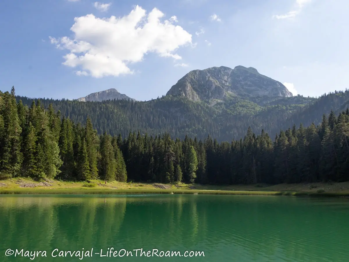 Two high peaks overlooking a calm lake with pine trees