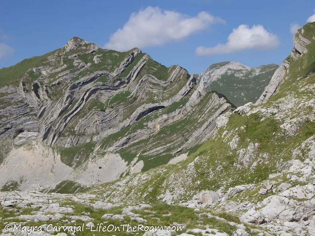 A mountain showing diagonal layers of vegetation and rocks