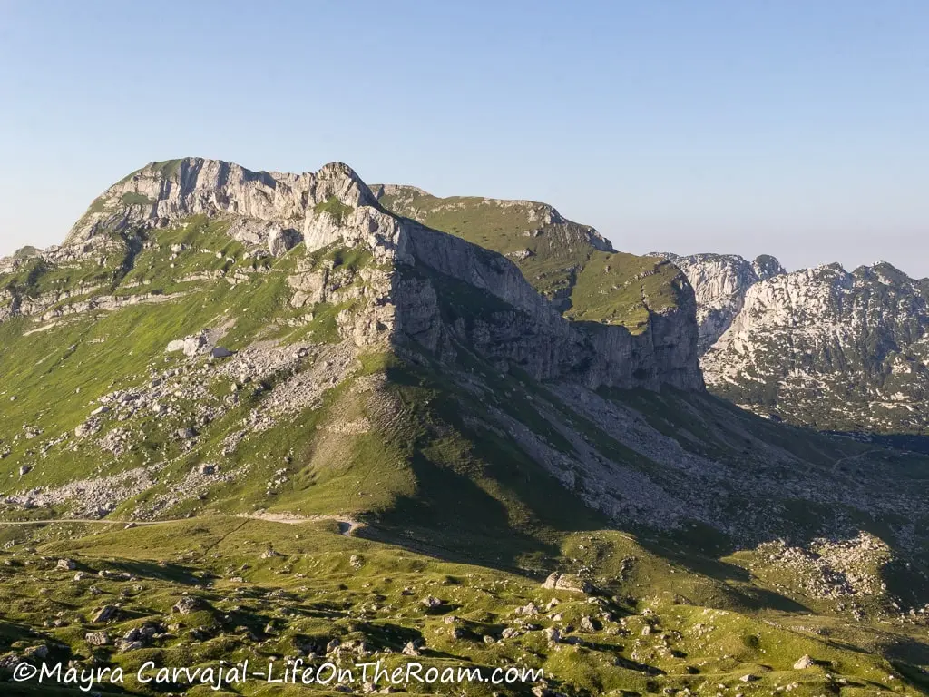 An expansive valley with grasses and a tall mountain ridge