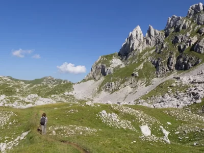 Mayra in a grassy valley between mountain peaks