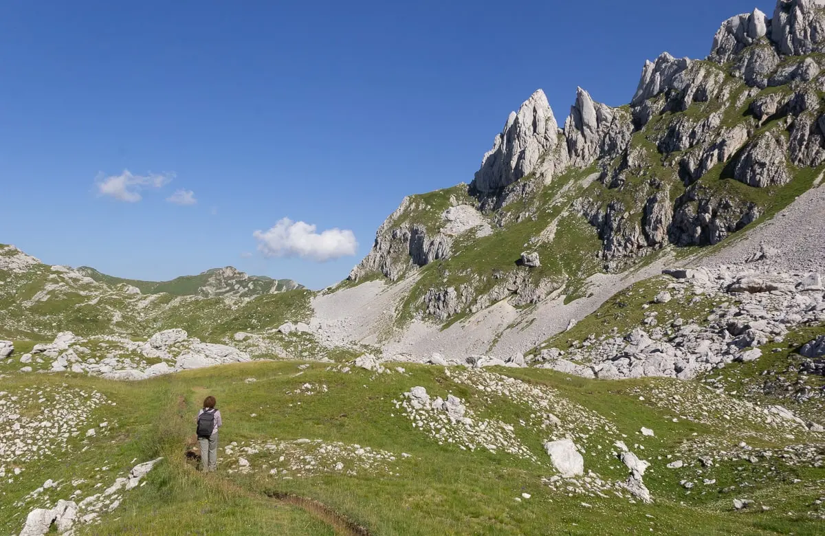 Mayra in a grassy valley between mountain peaks