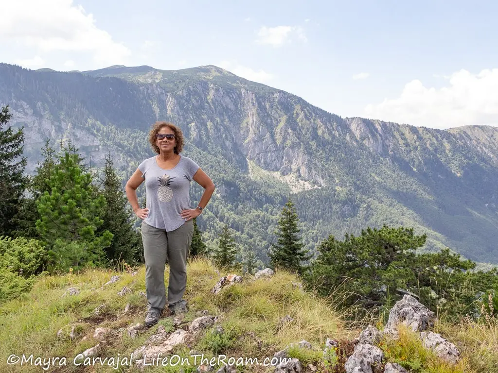 Mayra at a viewpoint with mountains in the background and pine trees