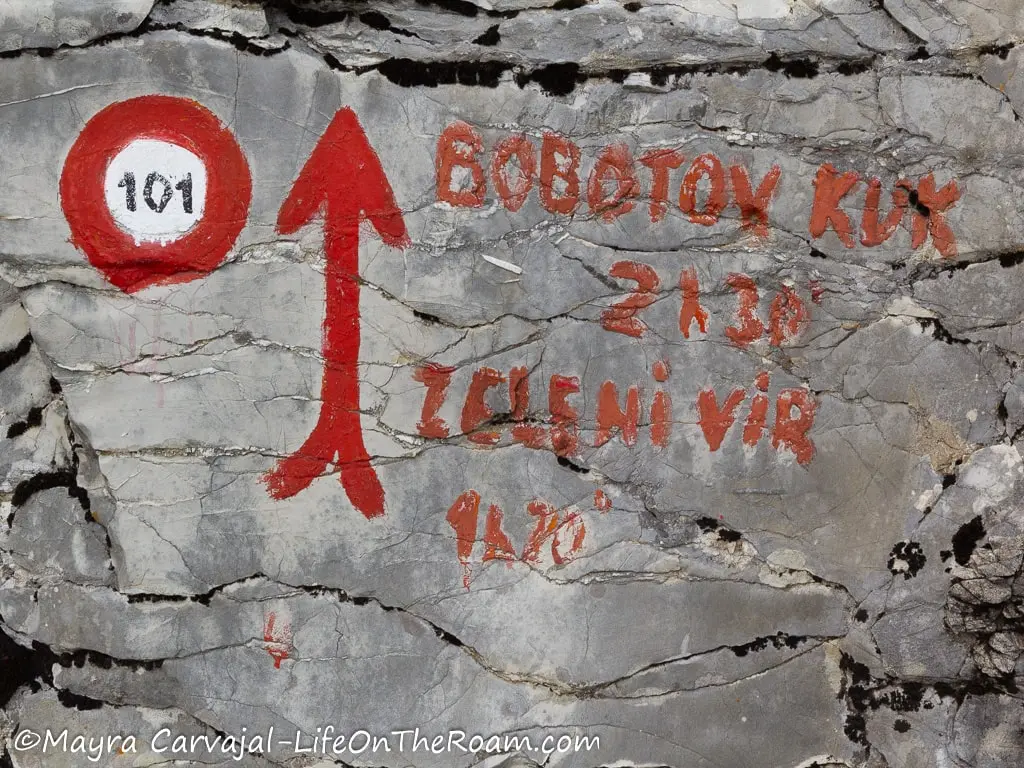 Signs (red circle with with centre) and red arrow with words "Bobotov Kuk" painted on a rock