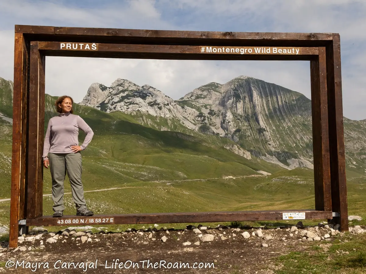 Mayra standing inside a giant frame outdoors framing a scenic mountain