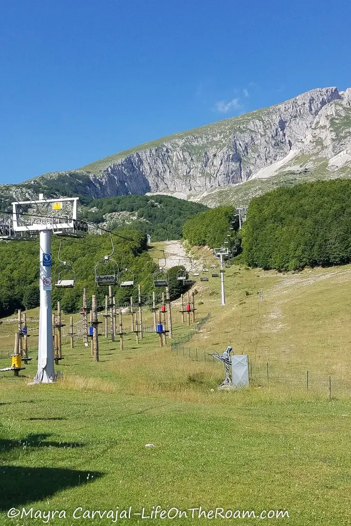 A ski lift with chairs towards a mountain in the summertime