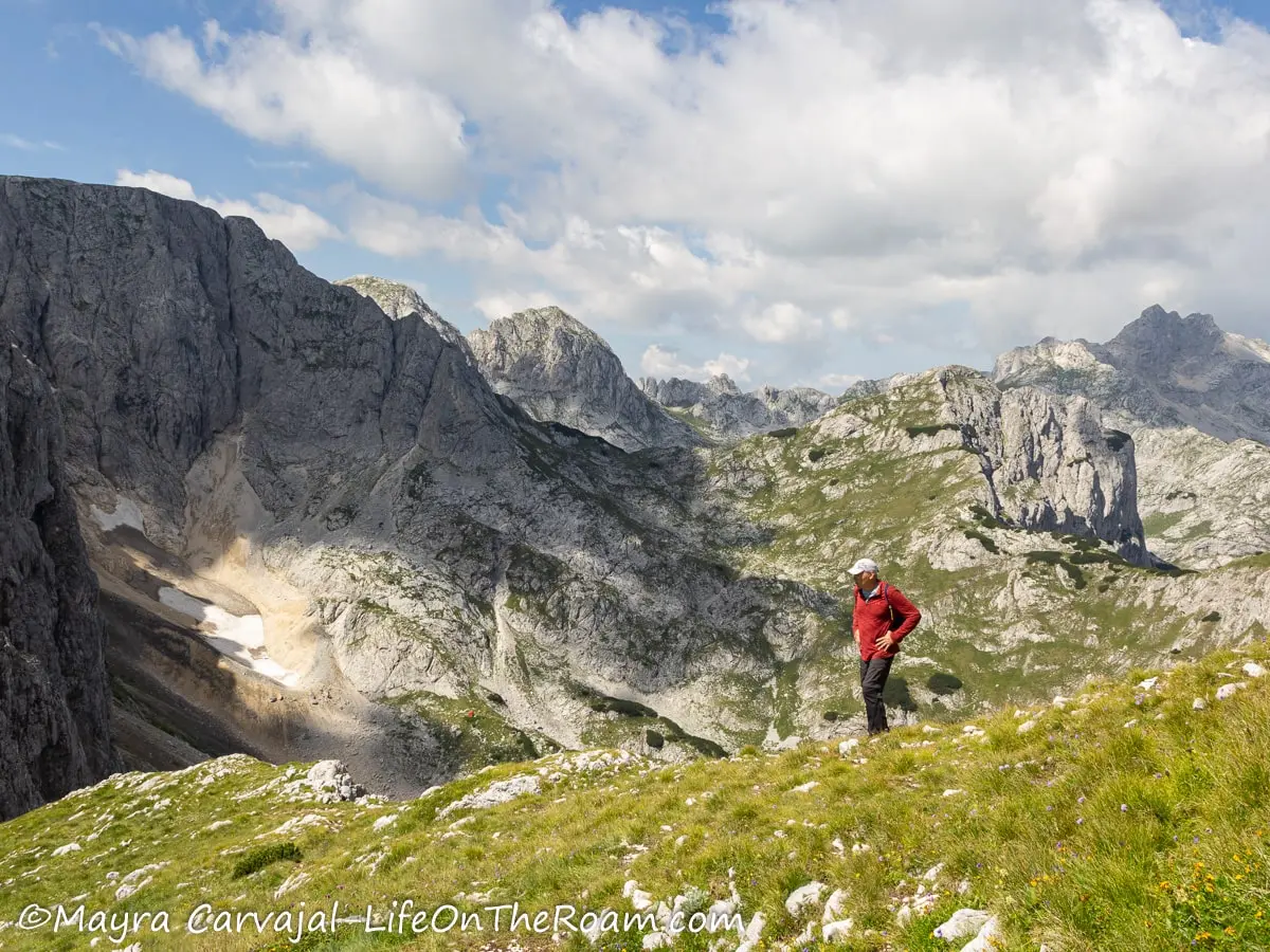 A man on a hiking trail among rugged mountain peaks