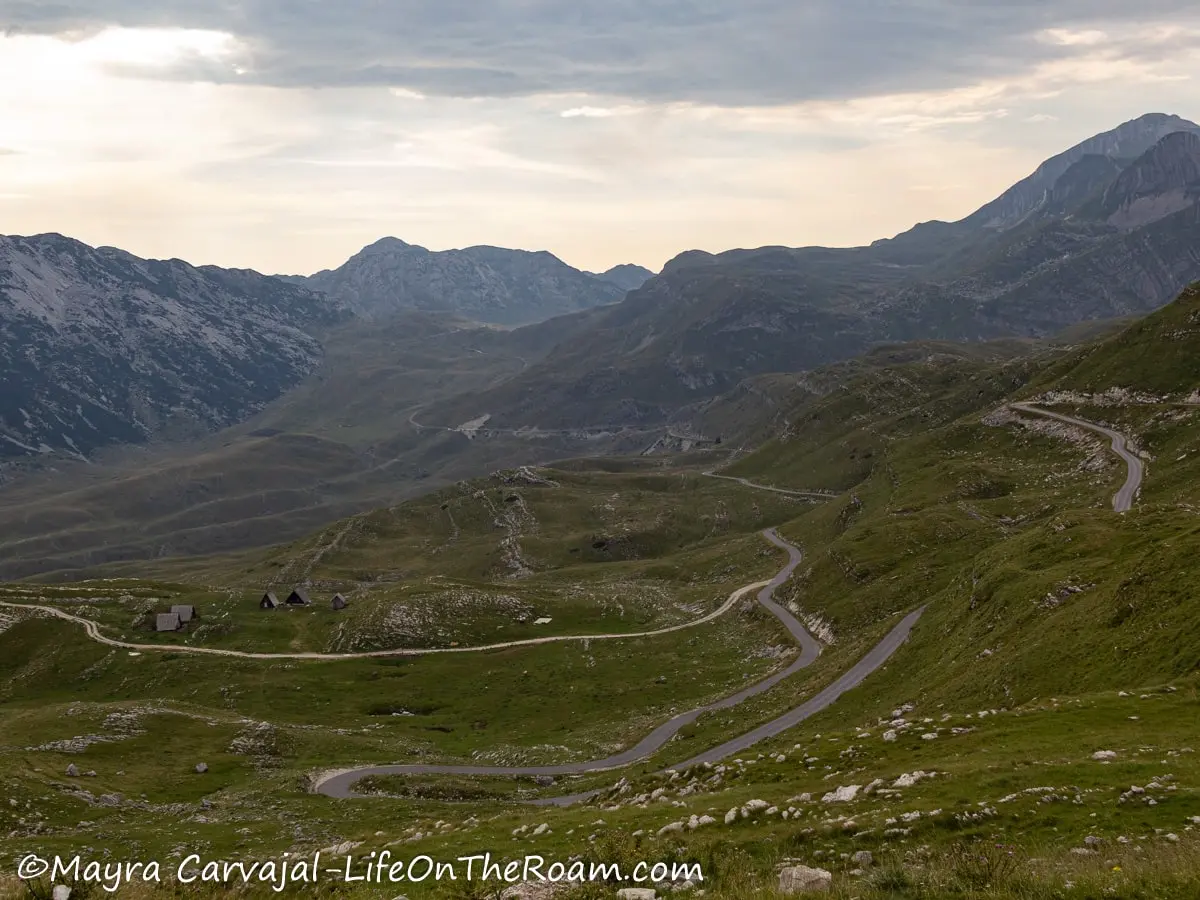 View of a paved road traversing a mountain valley with peaks in the distance