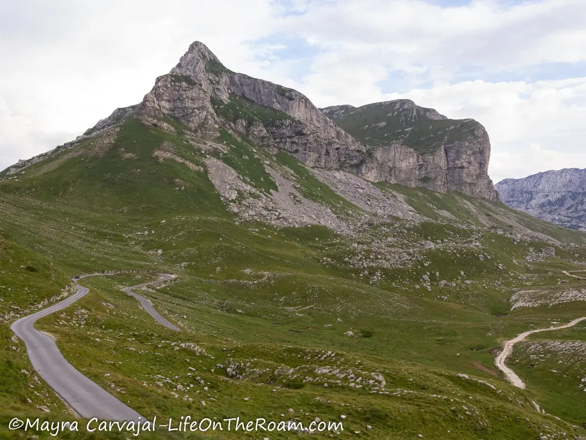 A mountain peak with rocks and vegetation along a paved road