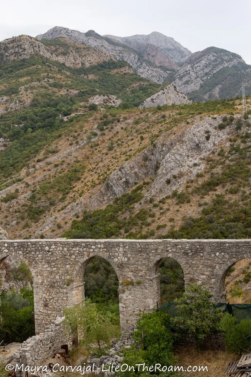 Section of an old aqueduct with arches, with a mountain in the background