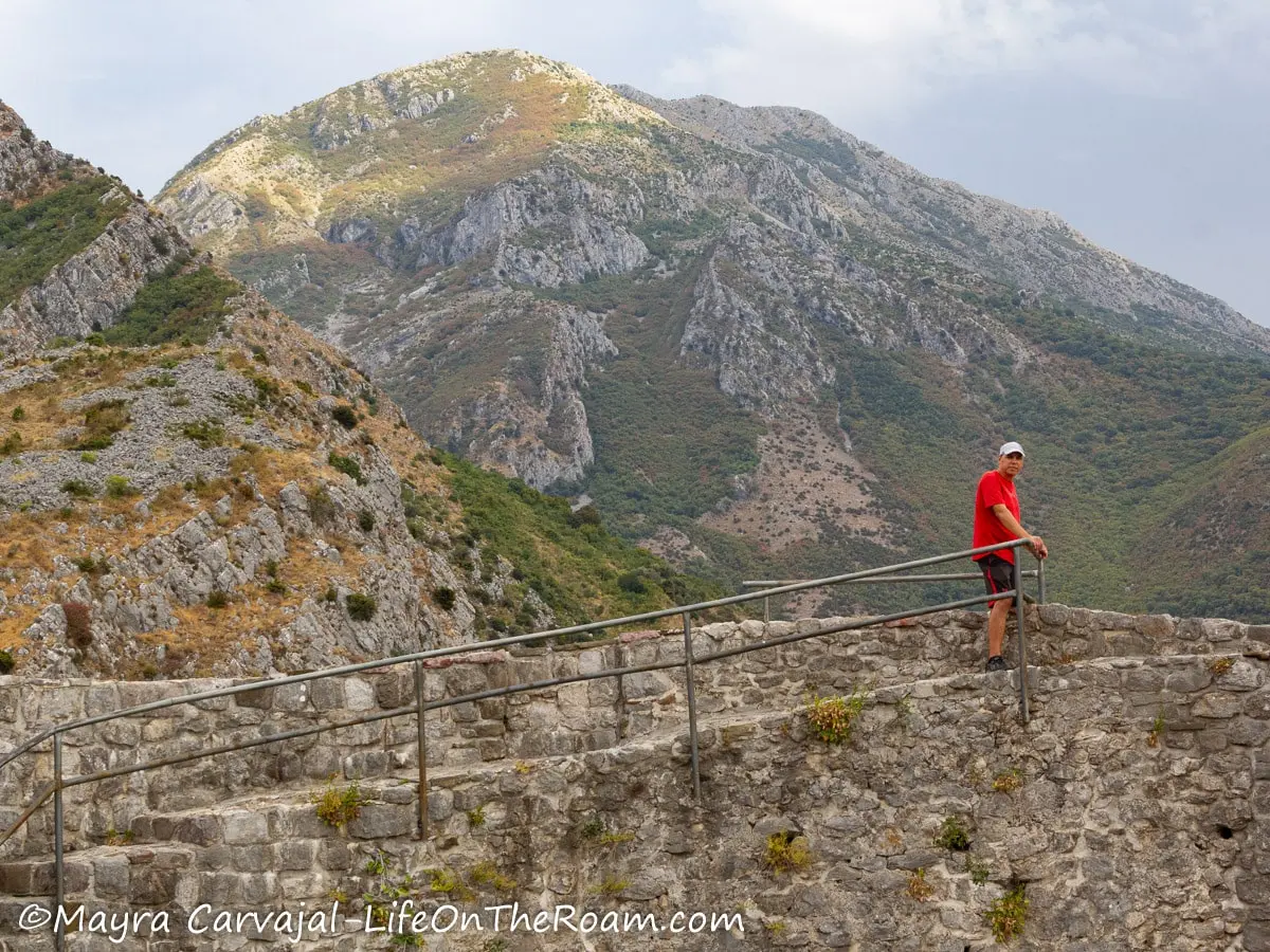 A man standing on a platform made of stone, with a view of a mountain