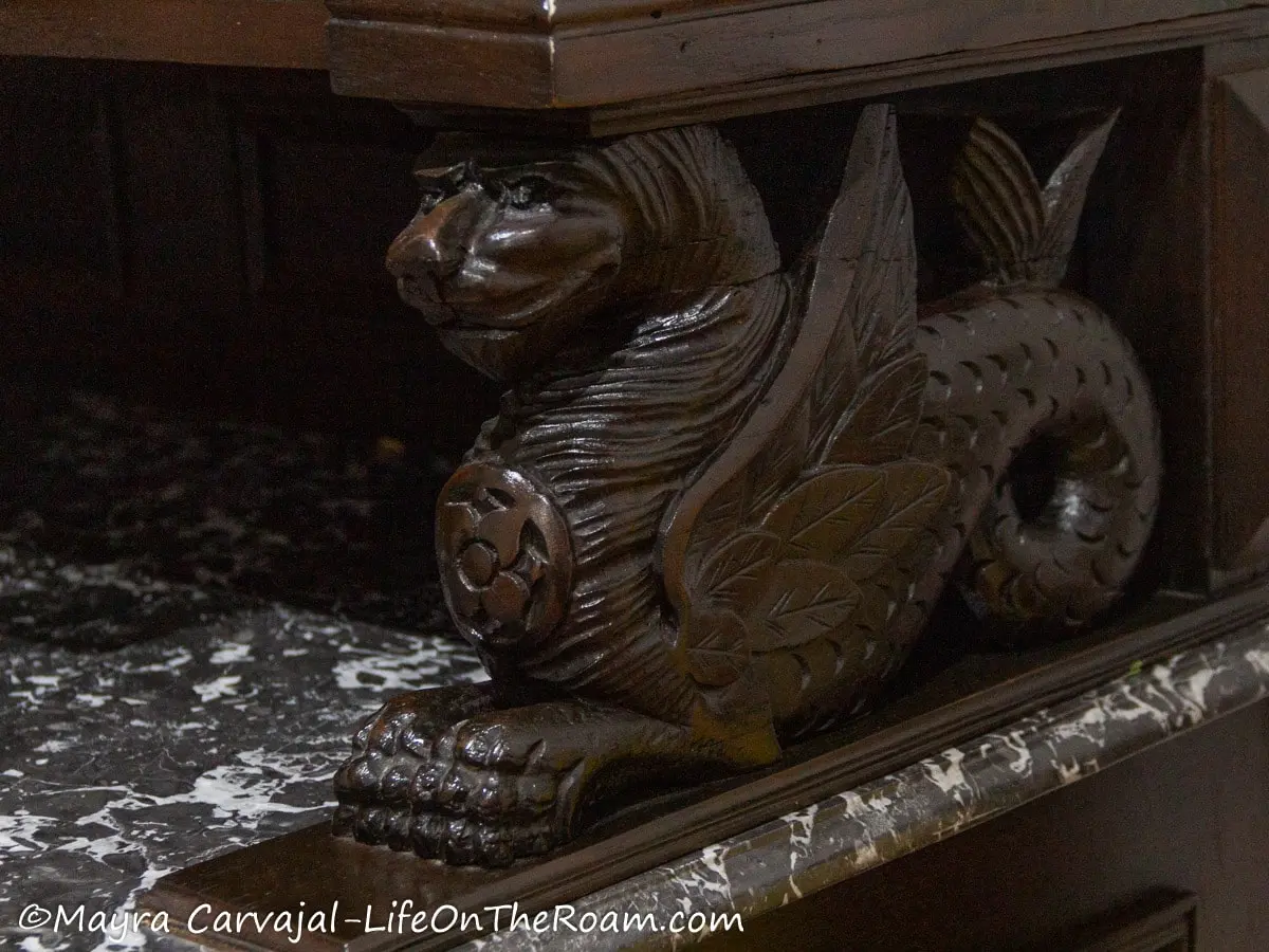 A wood carving of a winged lion on a furniture piece