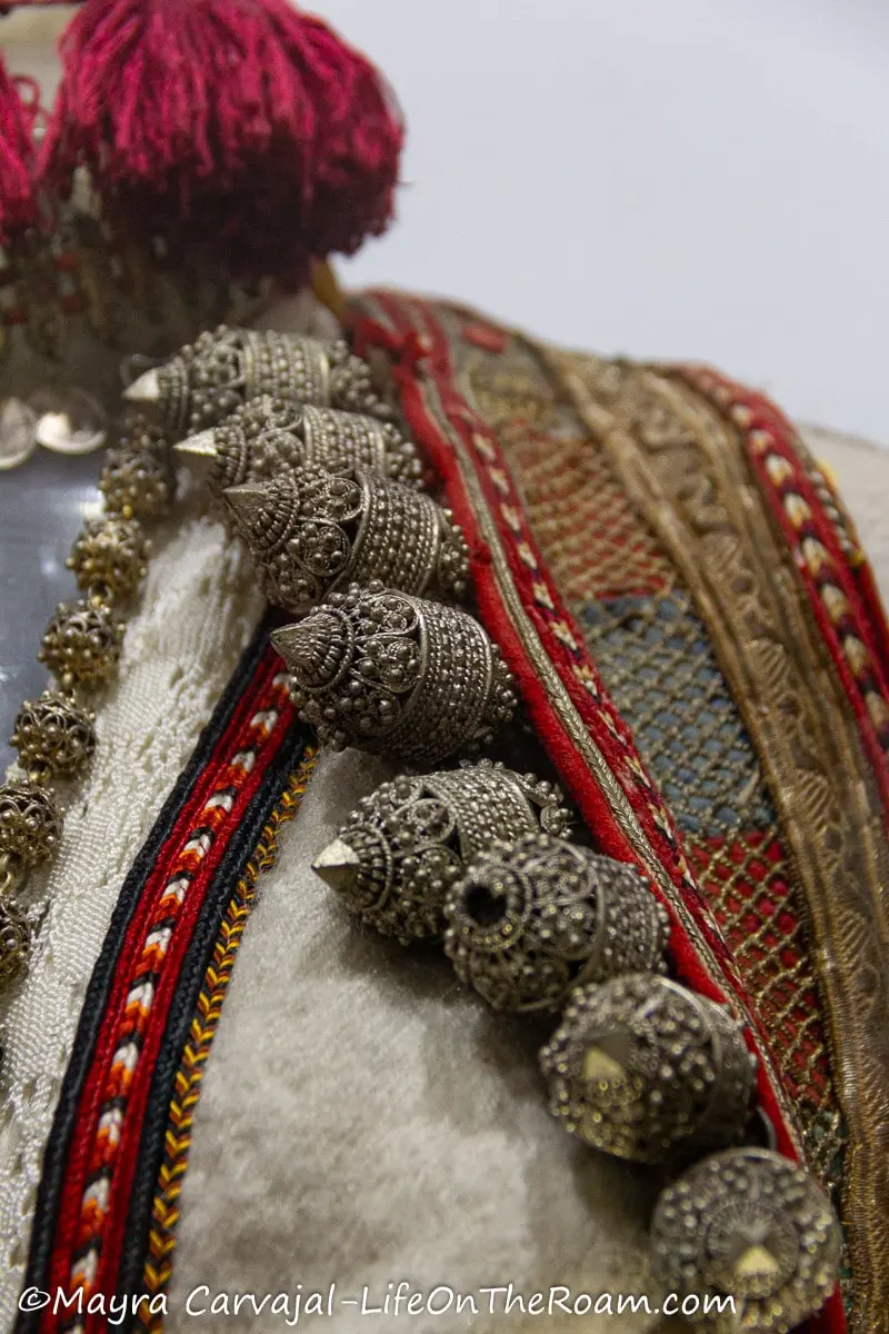 Decorative metal elements in the shape of cylinders on the chest section of a traditional custome