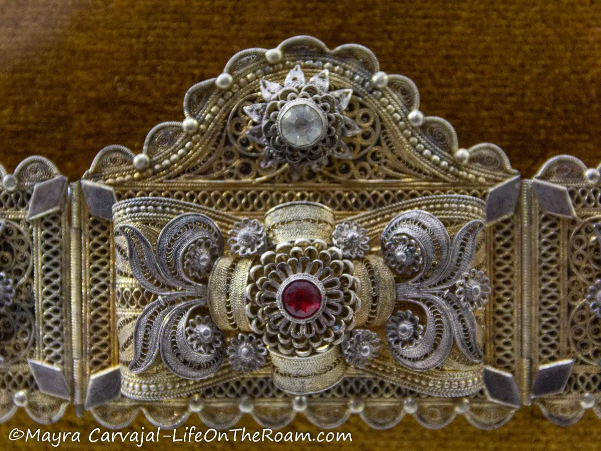 A highly intricate silver and gold-plated belt with decorative stones