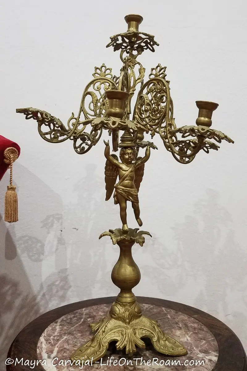 A golden metal candelabra in classical style with an angel at the base and curves.