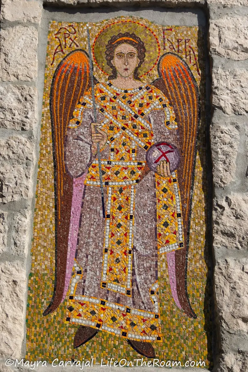 A multicolour mosaic on a wall with an angel in robes