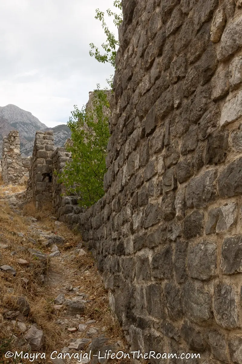 A dirt path along a cut stone wall