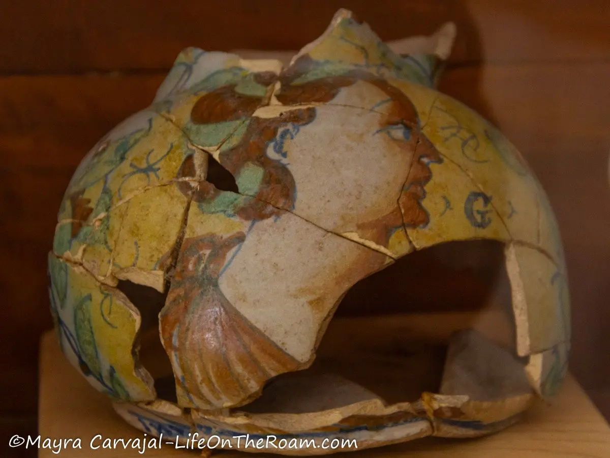 Fragments of colourful ancient pottery in the shape of a vase with the drawing of a human figure