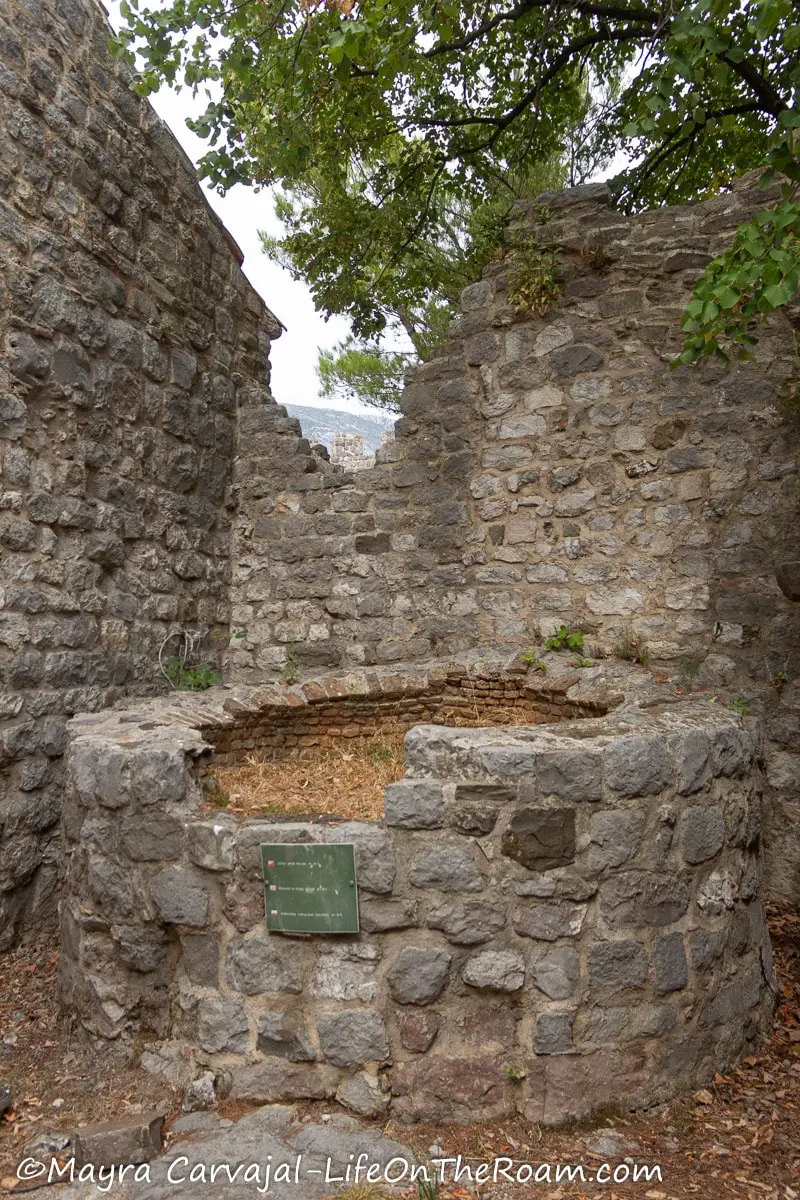 A big circular piece made in cut stone with partial height surrounded by stone walls