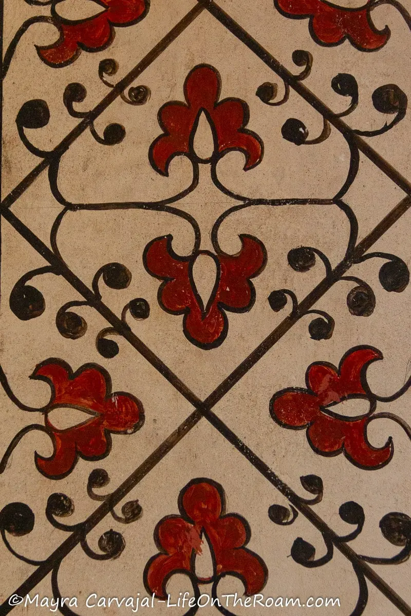 A hand painted pattern depicting a simple floral motif in red and black