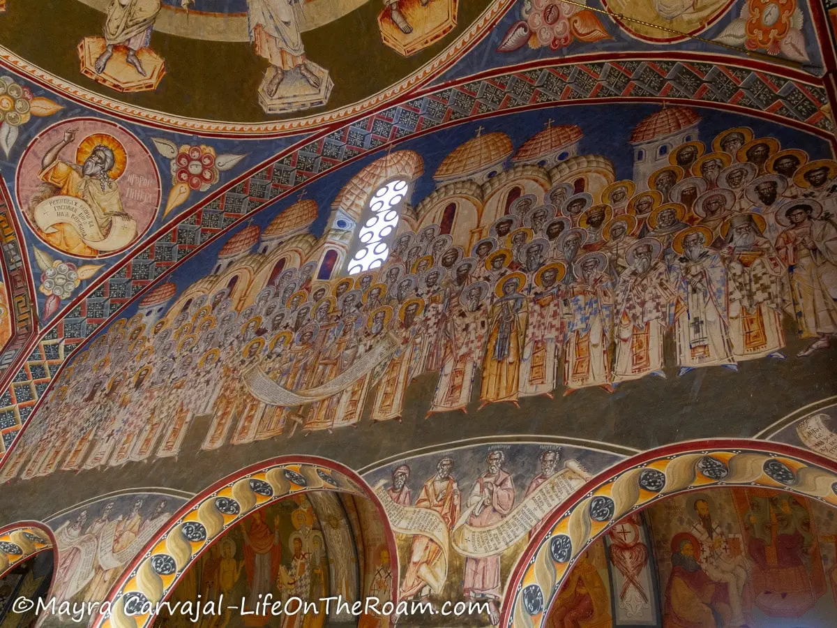 A mural covering the arched wall and ceiling of a church, depicting saints of the Orthodox church