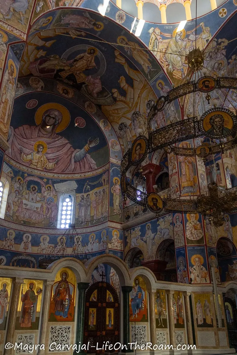 The altar section of a church with painted murals depicting biblical figures that cover the entire walls and domes