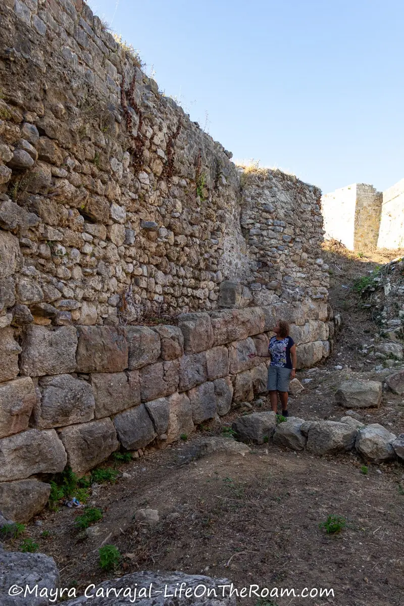 Mayra standing next to an old wall made of cut stone