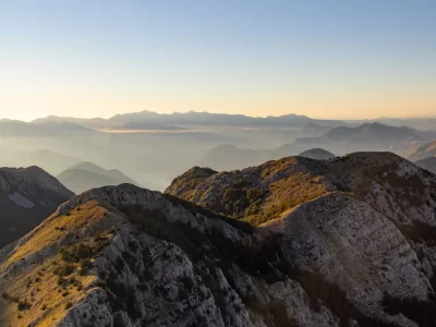 High view of a mountain system partially covered with vegetation and cloud in the distance, around sunset time