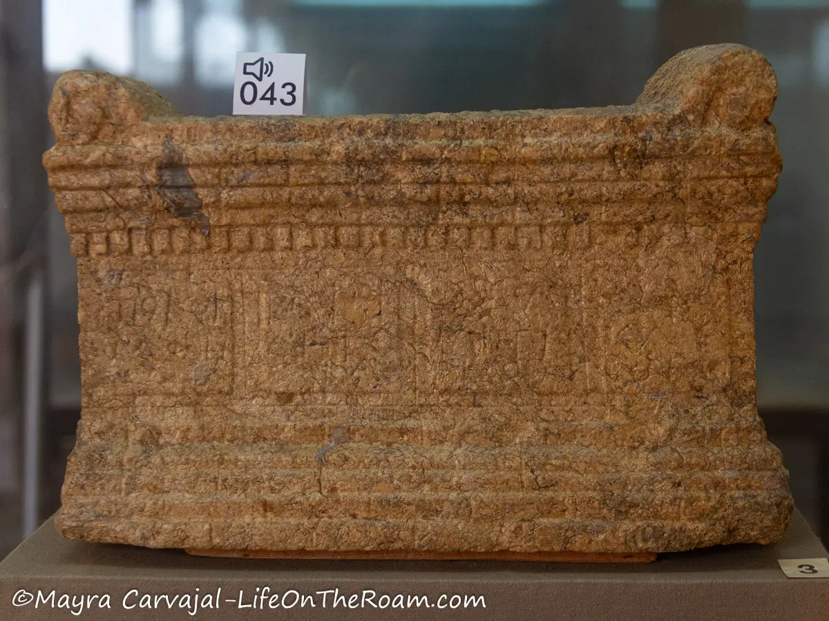 A rectangular urn in stone decorated with carvings