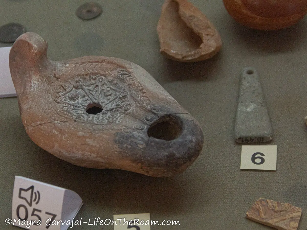 An ancient incense burner made of clay showing ornamental carvings and some burnt parts in the mouth